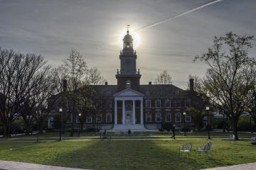Photo of Gilman Hall in which the sun is perfectly aligned with the spire.
