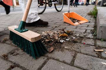 Broom sweeping debris toward a dustpan on a city street