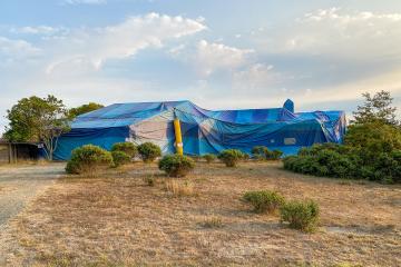 A large blue tent completely covers a home