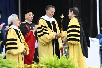 Mitt Romney shakes Ron Daniel's hand at JHU Commencement.
