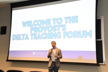 A large screen projected at the front of a lecture hall saying 