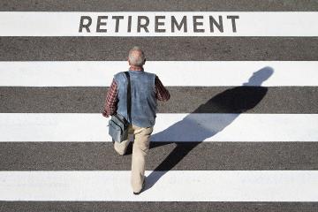 Man walking on a striped crosswalk toward the word retirement.