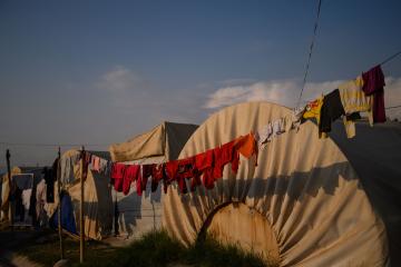 A clothesline strewn with drying clothes hangs in front of a tent at a refugee shelter in northern Iraq