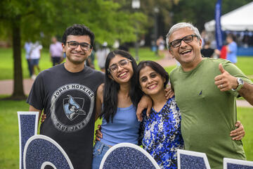 Four adults smile for the camera with their arms around each other.