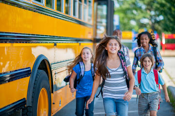 Smiling children leaving their school bus to enter their school