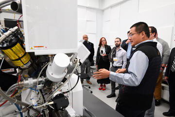 A group of people inspect some equipment in a lab setting