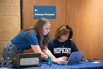 Meaghan McDermott, left, and Maria Harris Tildon at a table looking at a laptop