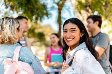 Smiling college student on her campus with friends in the background