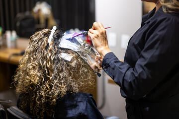 Hairdresser dyeing a woman's hair in a salon