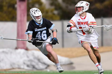 A lacrosse player in white tries to move past a defender in black