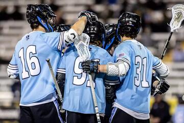 Lacrosse players in light blue gather to celebrate a goal