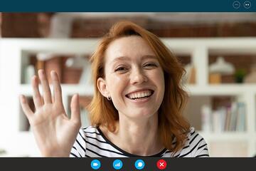 A young woman is seen on a monitor waving to other members of her virtual networking group.