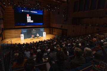 A large auditorium of people watch a live recording of "On with Kara Swisher."