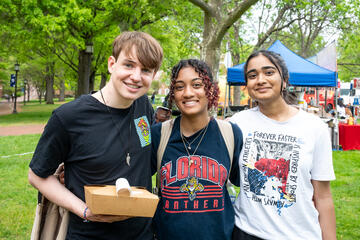 Three college students smile for the camera at Johns Hopkins Spring Fair.