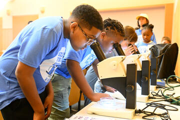 Young visitors looking through high-powered microscopes