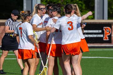 Women's lacrosse players in white and orange celebrate