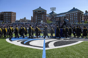 Master's degree candidates in the Whiting School of Engineering cross Homewood Field to the Commencement stage May 19