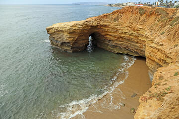 Sunset cliffs natural park in San Diego, California, a beach with a sandstone cliff and city buildings in the background