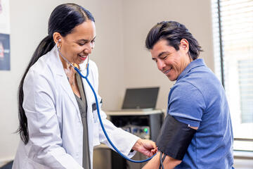 A female doctor checks her male patient's blood pressure