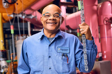 A man in glasses and a light blue work shirt poses for a photo