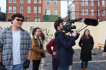 A group of film students with a camera and microphone in an urban playground setting