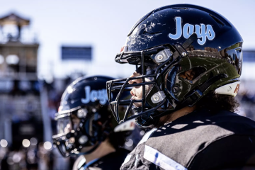 Two football players in black helmets that read "Jays"