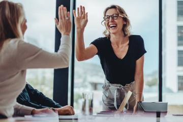 Two happy women high-fiving in an office