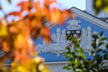 Orange fall leaves in front of the university seal on Shriver Hall