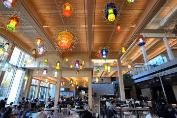 Multiple colorful light fixtures hang overhead in the food hall at the Bloomberg Student Center