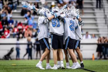 JHU men's lacrosse players hugging on the field