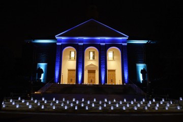 Front of Shriver Hall is illuminated in blue with luminaries on the steps