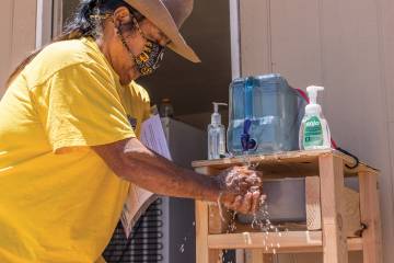 A resident of the Black Rock community of the Navajo Nation uses a hand-washing station provided by the Center for American Indian Health.