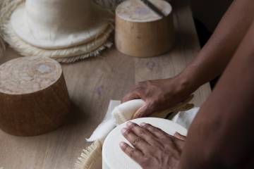 An artisan works with a nearly finished Panama hat