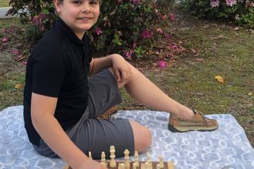 A boy plays chess outdoors
