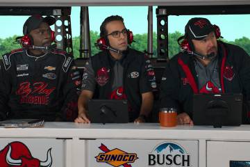 Dan Ahdoot (center) in a scene with actors Gary Anthony Williams (left) and Kevin James. The actors are wearing headsets and wearing racing gear.
