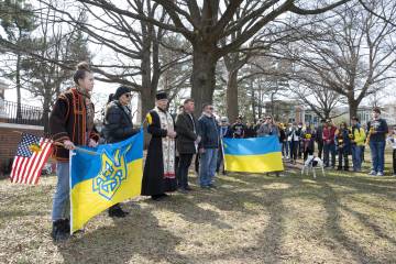 People hold large Ukrainian flags at a vigil 
