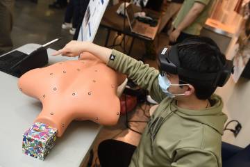 A person wearing virtual reality goggles looks at a CPR mannequin