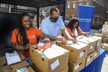 Representatives from Johns Hopkins and various community organizations prepare to distribute boxes of supplies to the community