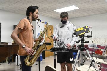 A saxophone player plays while student record