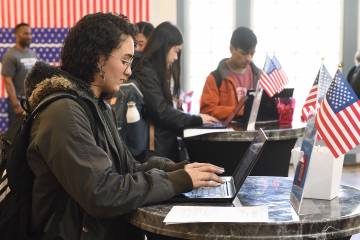 Students type on laptops next to American flags and bunting
