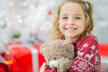 Smiling young girl hugging a teddy bear