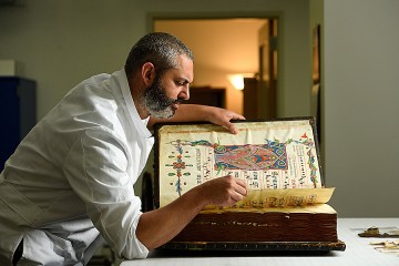 Book conservator Alessandro Scola with the 40-pound medieval manuscript he's currently working on.