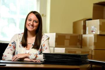 Amanda Bauer surrounded by boxes of diplomas.