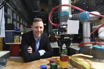Andrew Hundt sits beside his block-stacking robot