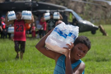 A boy carries a case of water
