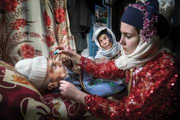 A woman administers eyedrops to her grandfather
