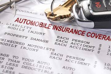 Auto insurance policy with car keys and glasses on top of it