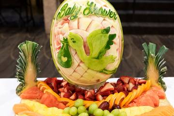 Fruit display with the words baby shower and a stork carved into a watermelon rind