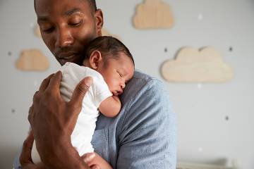 Father holding newborn on his shoulder