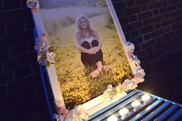 Portrait photograph of Abby Bastien adorned with flowers and lit by tea light candles